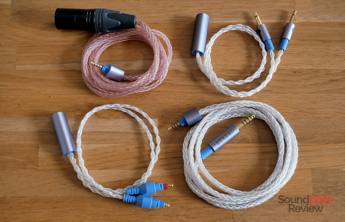 Picture showing four Dekoni Ensemble modules: XLR4 pre-split with a copper cable, 3.5 mm jack post-split with an SPC cable, Sennheiser HD6xx post-split with an SPC cable, and 4.4 mm jack pre-split with an SPC cable.